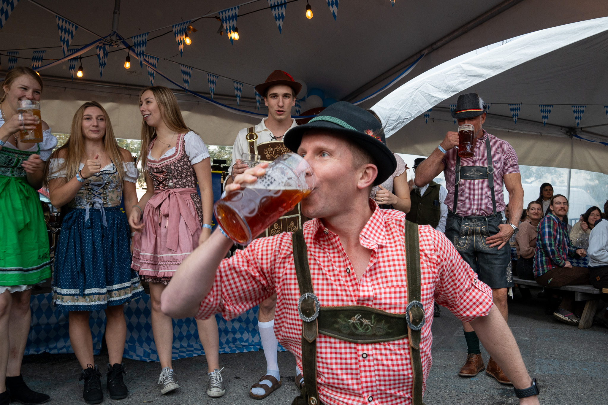 a man dressed in a bavarian outfit drinking a stein of beer at a beer festival